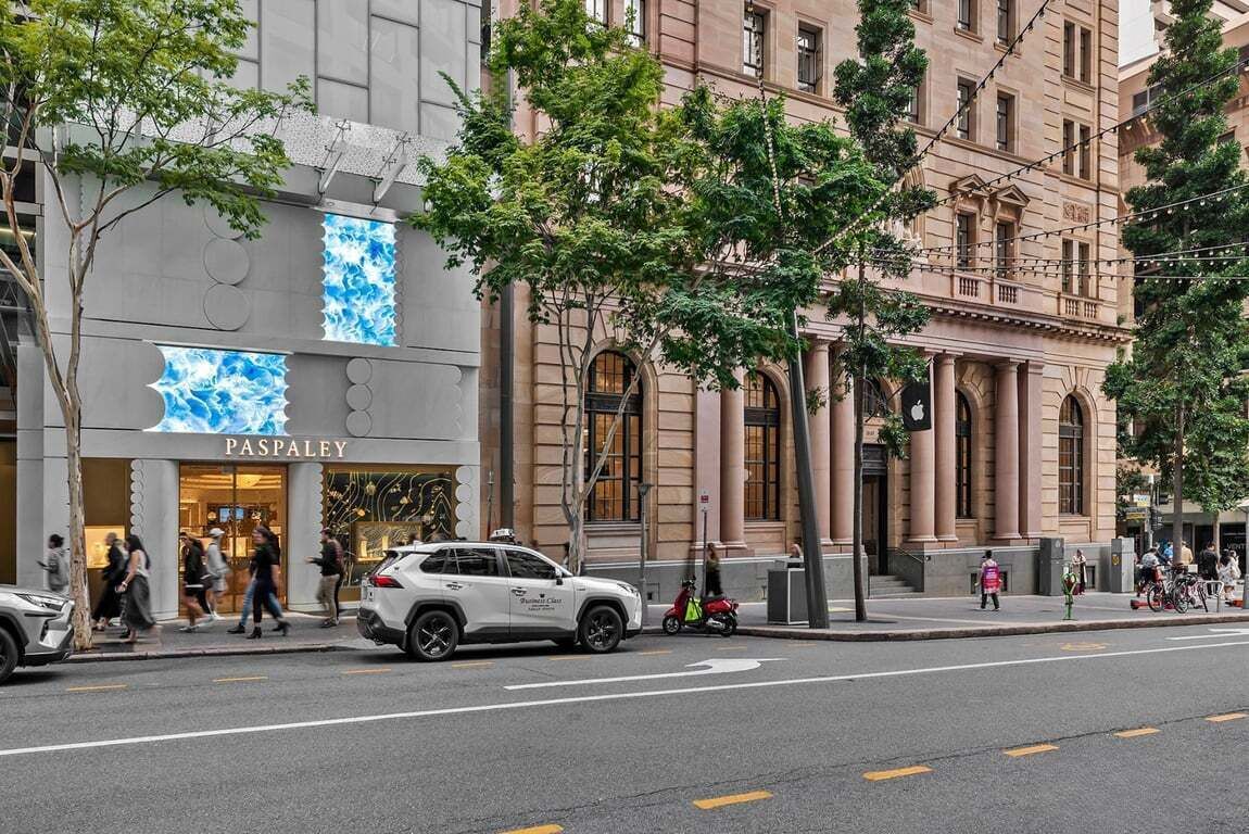 A street view with a building labeled 'PASPALAY' and a white SUV parked on the sidewalk.