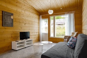 Ein Holzblock-Interieur mit Fernseher, Sofa und zwei kleinen Tischen.