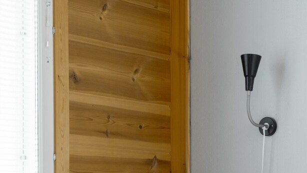 A bed with white bedding, a wooden headboard, and a wall-mounted lamp. - Apartment A 3 Talja, Private Sauna By Lapland Host (Rovaniemi)