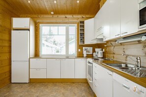 Cocina compacta con armarios blancos, horno integrado y ventana que proporciona luz natural.