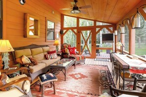 Un acogedor interior de cabaña con sofá, sillones, una mesa de comedor y un televisor.