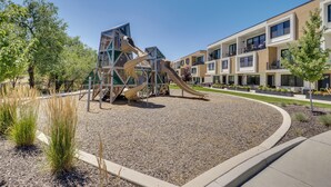 A playground with slides and climbing structures, surrounded by a landscaped area with trees and shrubs. - Brand-New Townhome Near Dtwn Salt Lake & Trails! (Millcreek)