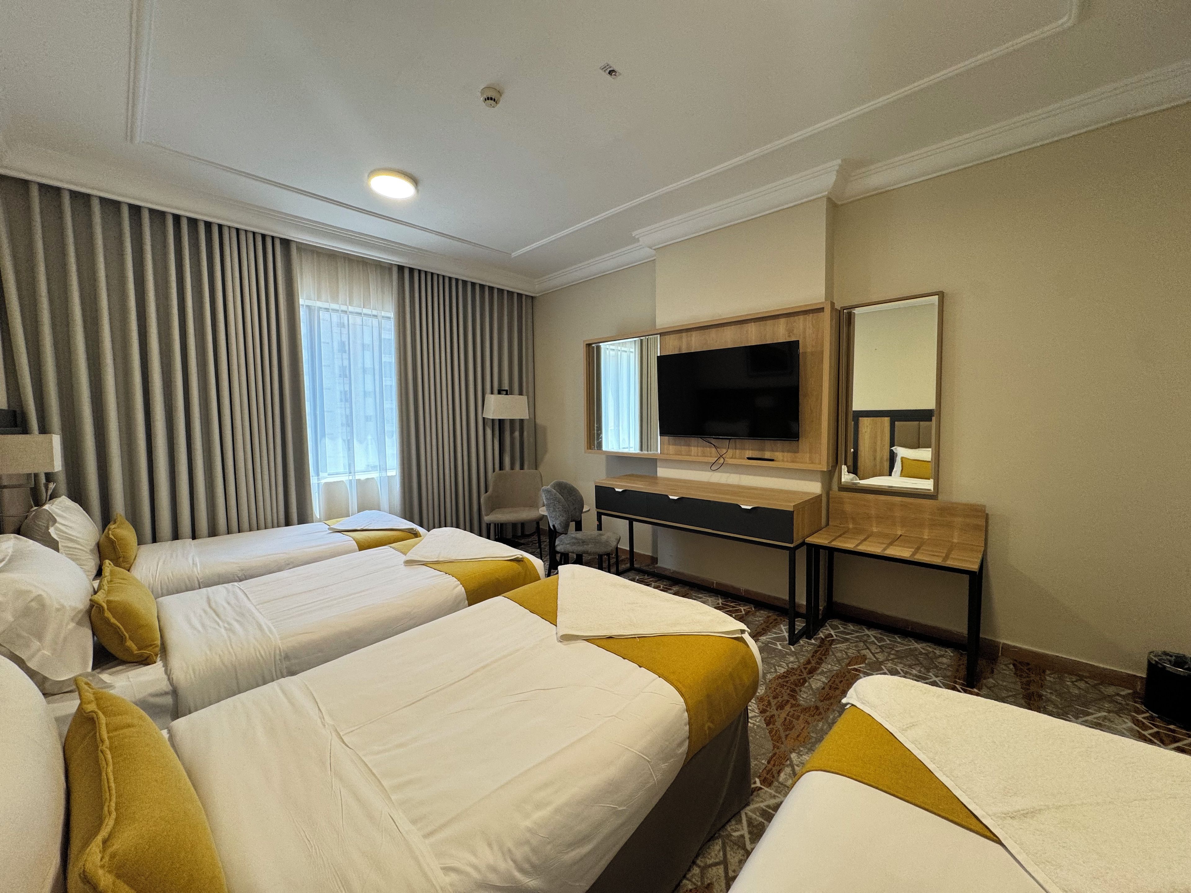 Een hotelkamer met twee bedden, een bureau, een televisie en een spiegel.
