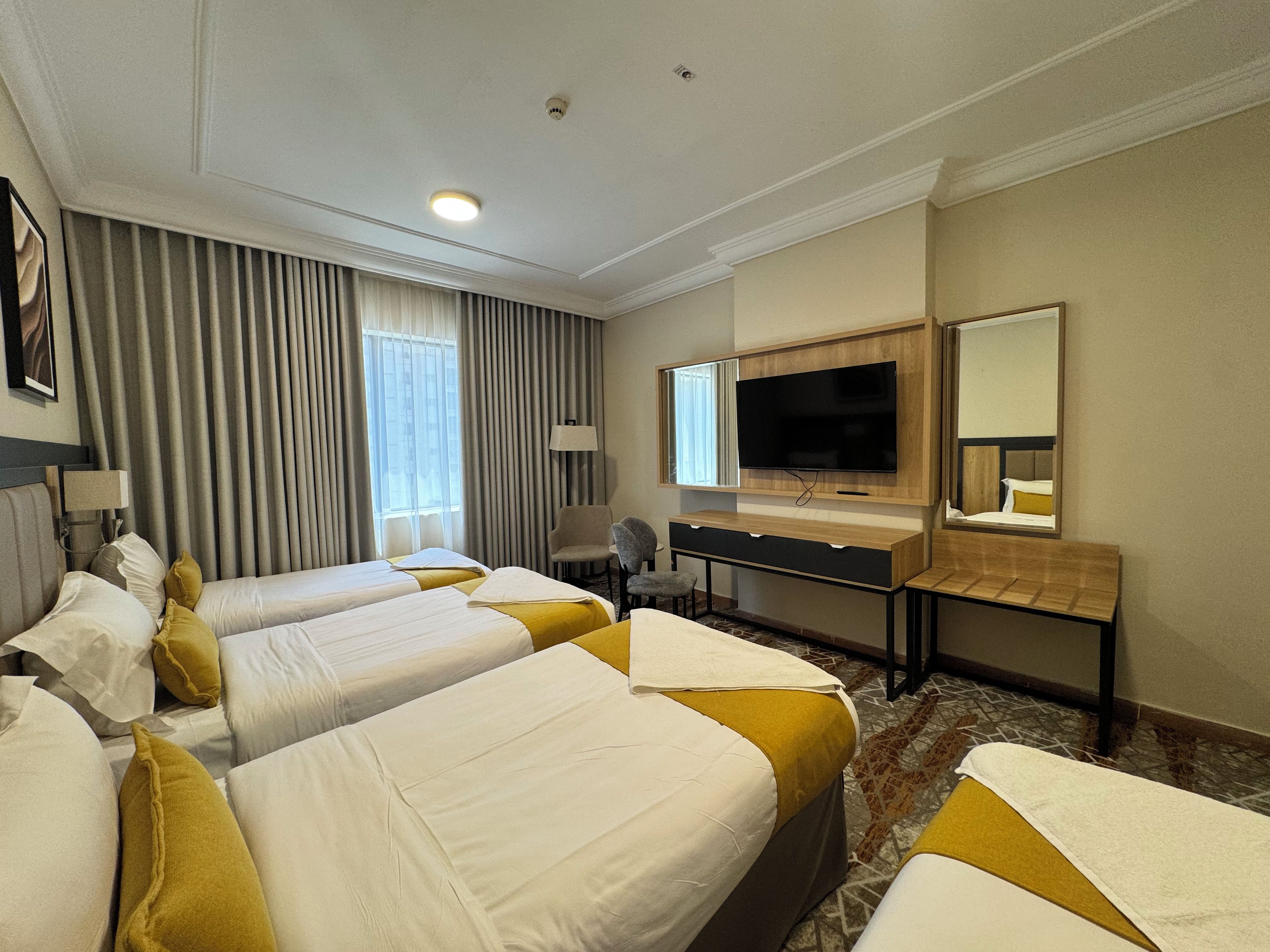 Une chambre d’hôtel avec deux lits, un bureau, une télévision et un miroir.
