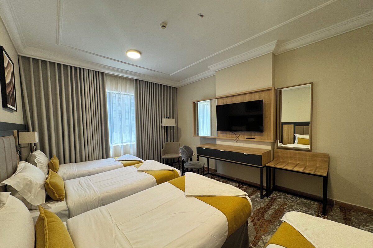 Une chambre d’hôtel avec deux lits, un bureau, une télévision et un miroir.