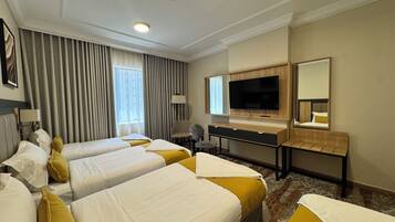 A hotel room with two beds, a desk, a television, and a mirror.