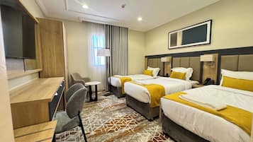 Habitación de hotel con dos camas, un escritorio, una silla, un televisor y una alfombra estampada.