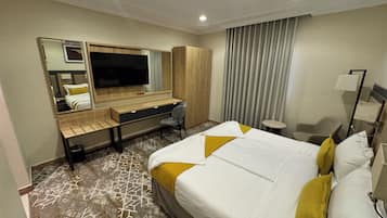 Ein Hotelzimmer mit Bett, Schreibtisch, Stuhl, Fernseher und Kleiderschrank.