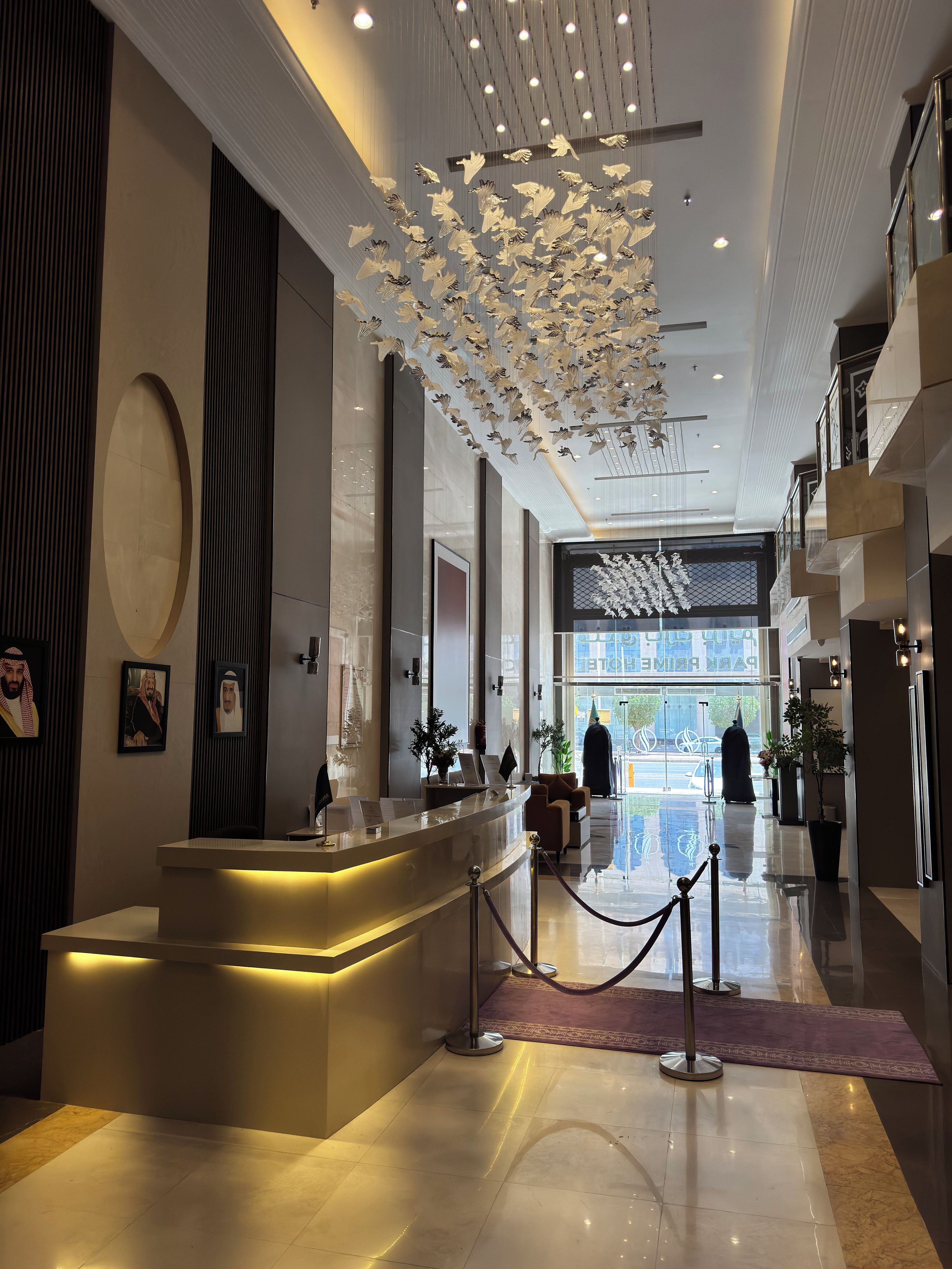 Un moderno hall de hotel con una recepción, un techo decorativo y vistas a la calle.