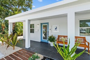 A modern building with a white exterior, a blue door, and a wooden bench outside. - Private Pool + Firepit + Beach Gear | Short Drive to Beach + Las Olas | Al Mare (Fort Lauderdale)