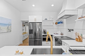 Eine moderne Küche mit weißen Schränken, Edelstahlgeräten und einer Holzausziehtafel.