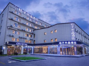 Un hôtel à plusieurs étages, doté d’une entrée imposante avec des portes en verre et d’une enseigne indiquant le nom « Crystal ».