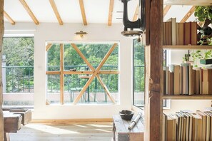 A room with a large window, wooden beams, a bookshelf, and a table with a bowl. - Balcony to Central Garden w AC - Vintage Library (Lisboa)