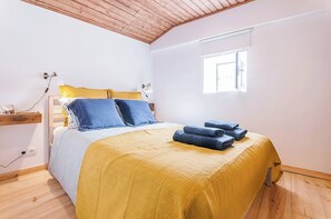 Ein Schlafzimmer mit einem Bett, einem Nachttisch, einer Lampe, einem Fenster und einer Steckdose.