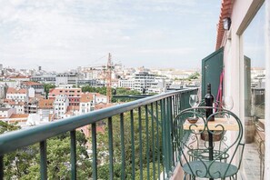 A balcony with a view of a cityscape, including buildings and a construction crane. - Balcony to Central Garden w AC - Vintage Library (Lisboa)