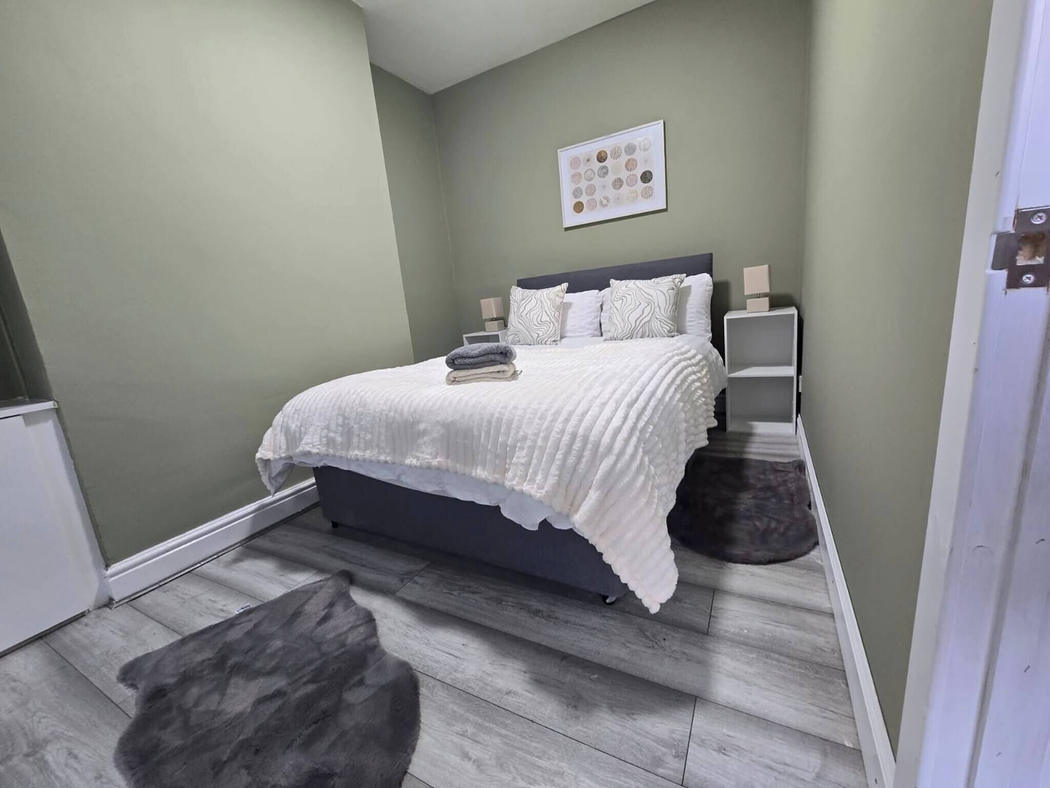 A bedroom with a bed, bedside tables, a rug, and a wall art piece.