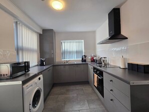 A compact kitchen with a washing machine, a toaster, and a coffee maker. - Cozy House in Liverpool (Kensington)