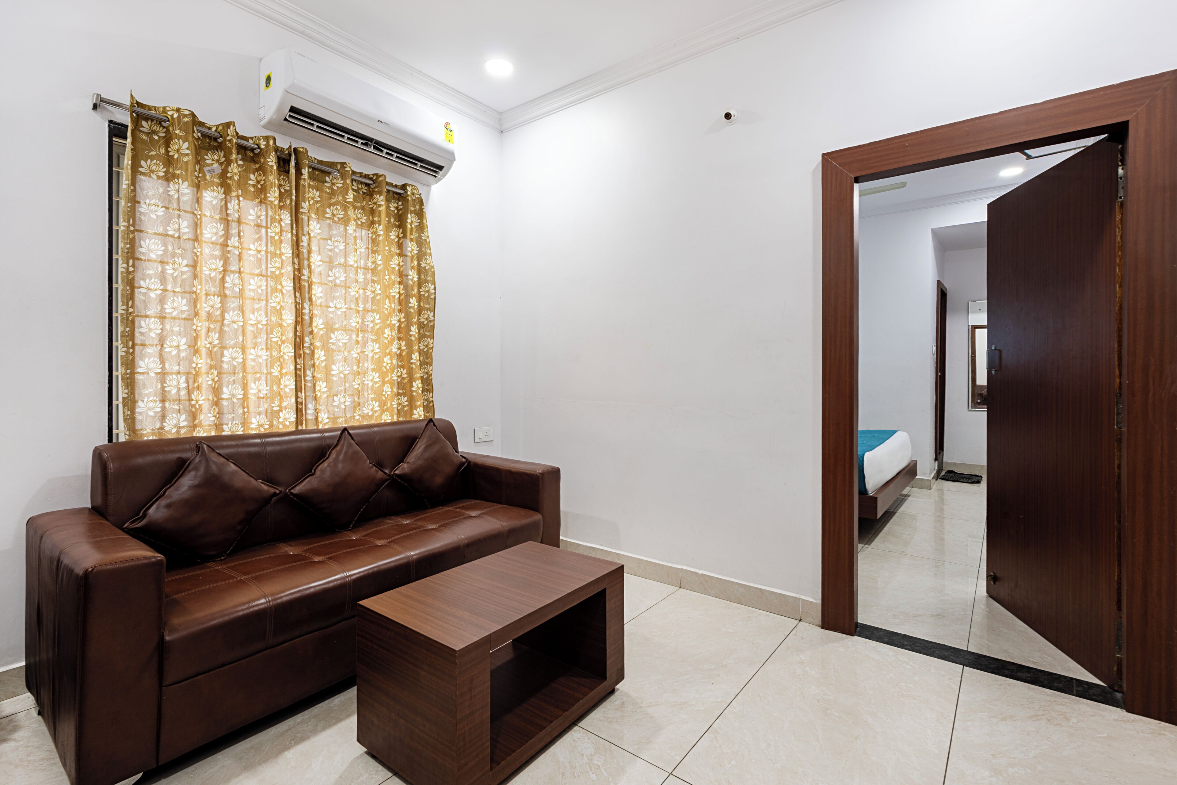 A room with a brown leather sofa, a wooden coffee table, and a large mirror on the wall.