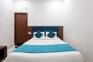 Un dormitorio con una cama, una puerta de madera y una pared blanca.