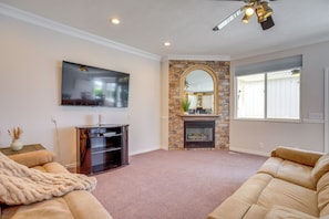 A living room with a flat-screen TV, stone fireplace, and a ceiling fan. - Near Hill AFB! Dual-Unit Home w/ Deck & Patio (Clearfield)
