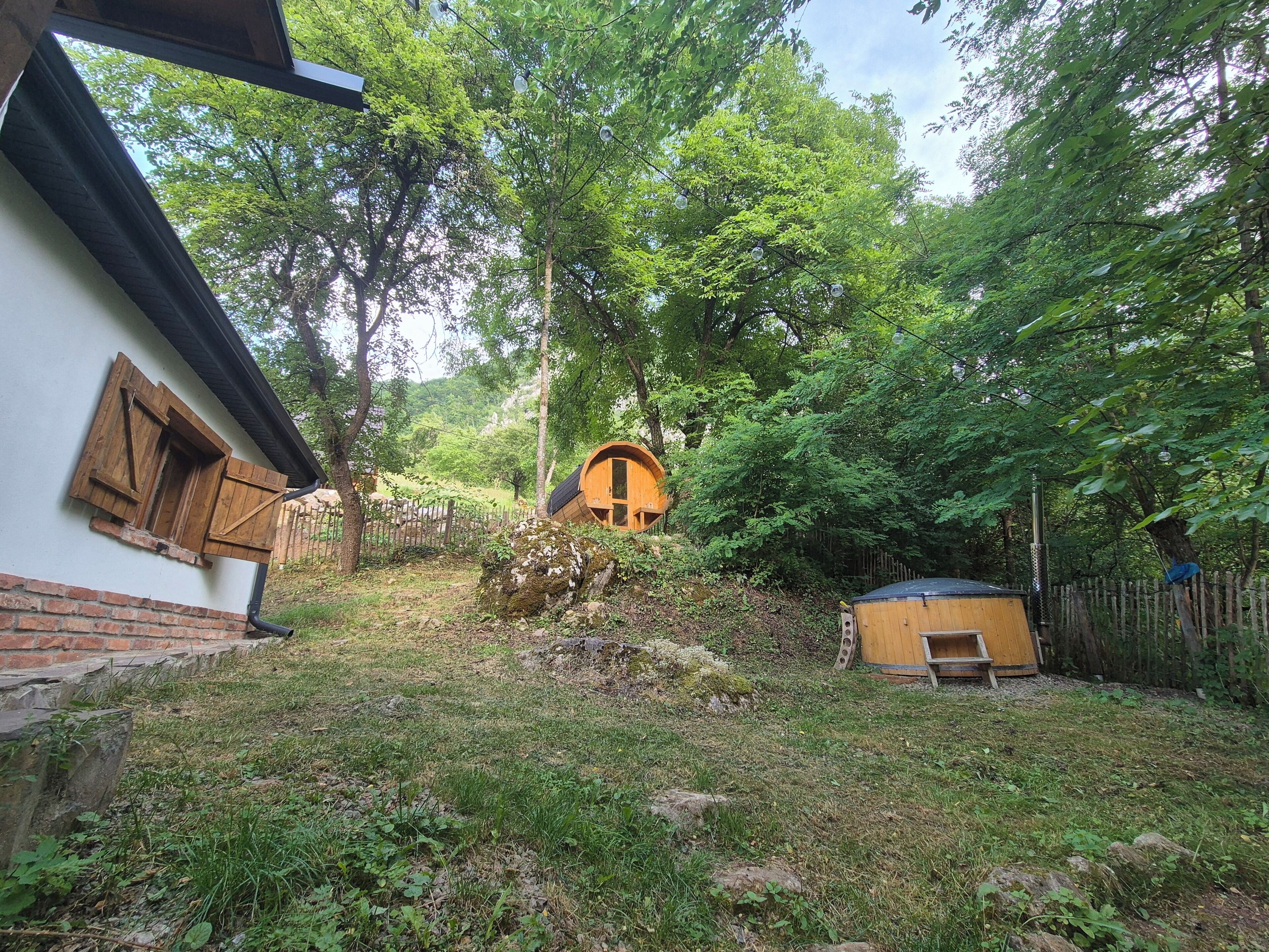 Une cabane rustique aux murs en bois, entourée d’un paysage naturel composé d’arbres et d’une petite construction en bois.