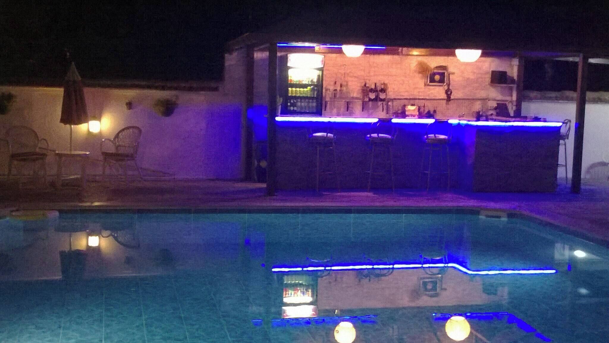 A pool area with a bar and chairs.