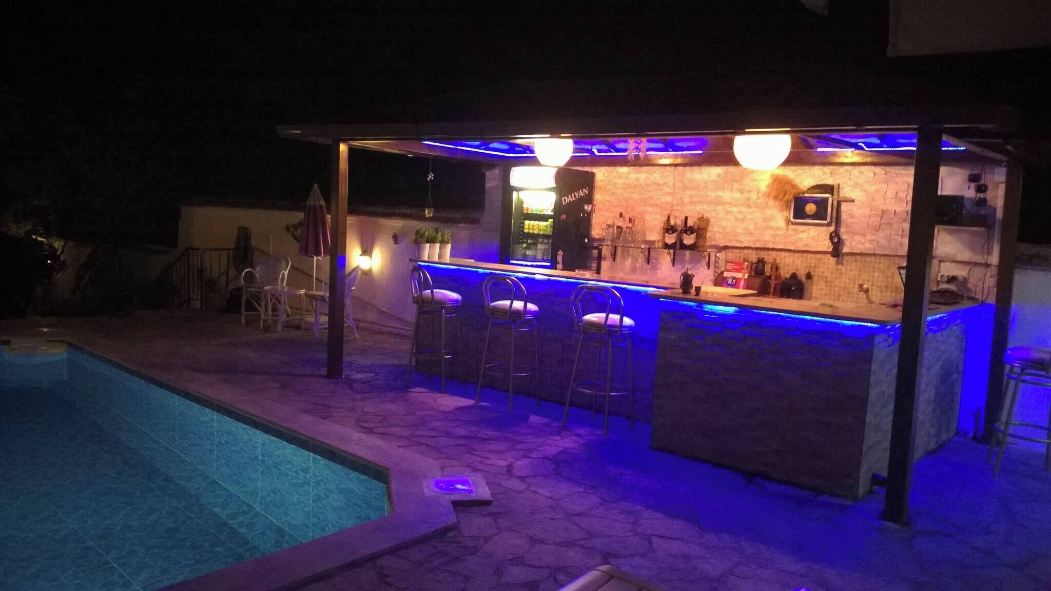 An outdoor bar area with a pool, bar stools, and a counter with a beverage dispenser.