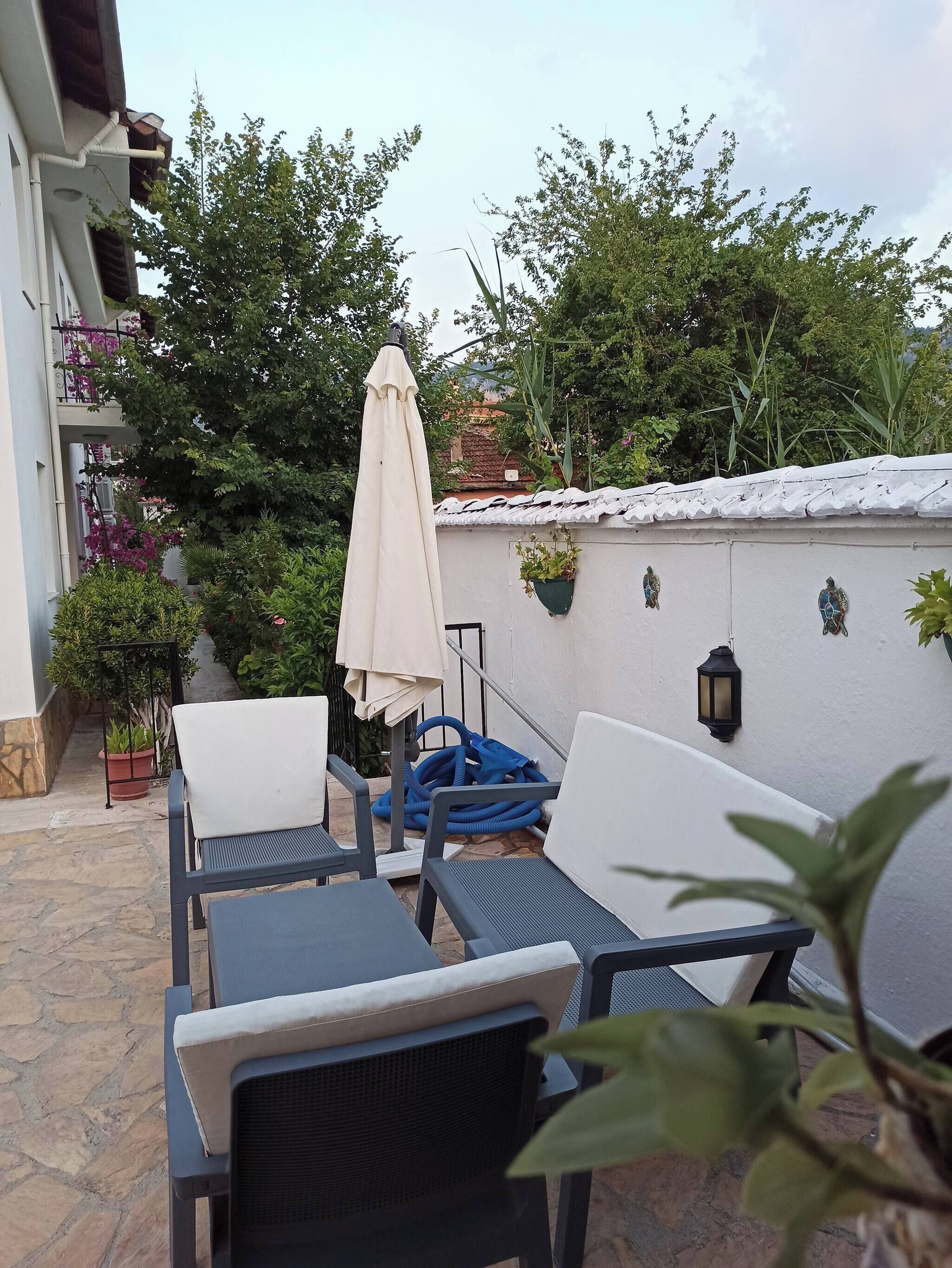 An outdoor seating area with chairs and tables, a white umbrella, and potted plants.