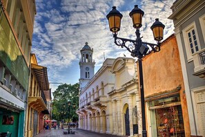 Calle con edificios históricos, una torre del reloj y un farol.