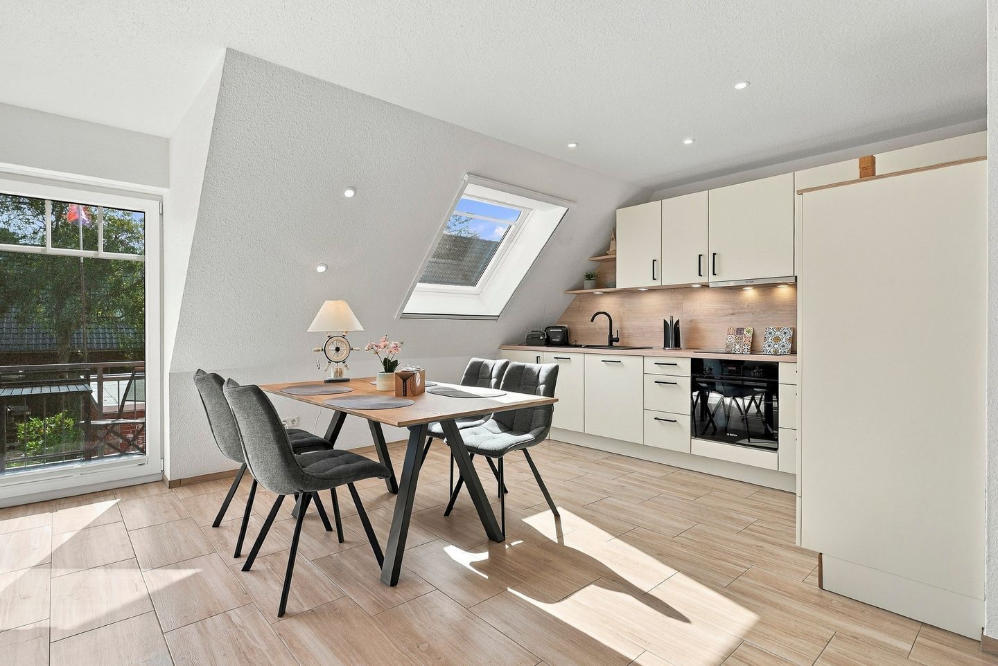 Una cocina moderna con tragaluz, un comedor con mesa y sillas, y vistas al exterior.