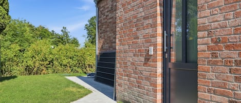 A modern brick building with a glass door and a metal vent on the side.