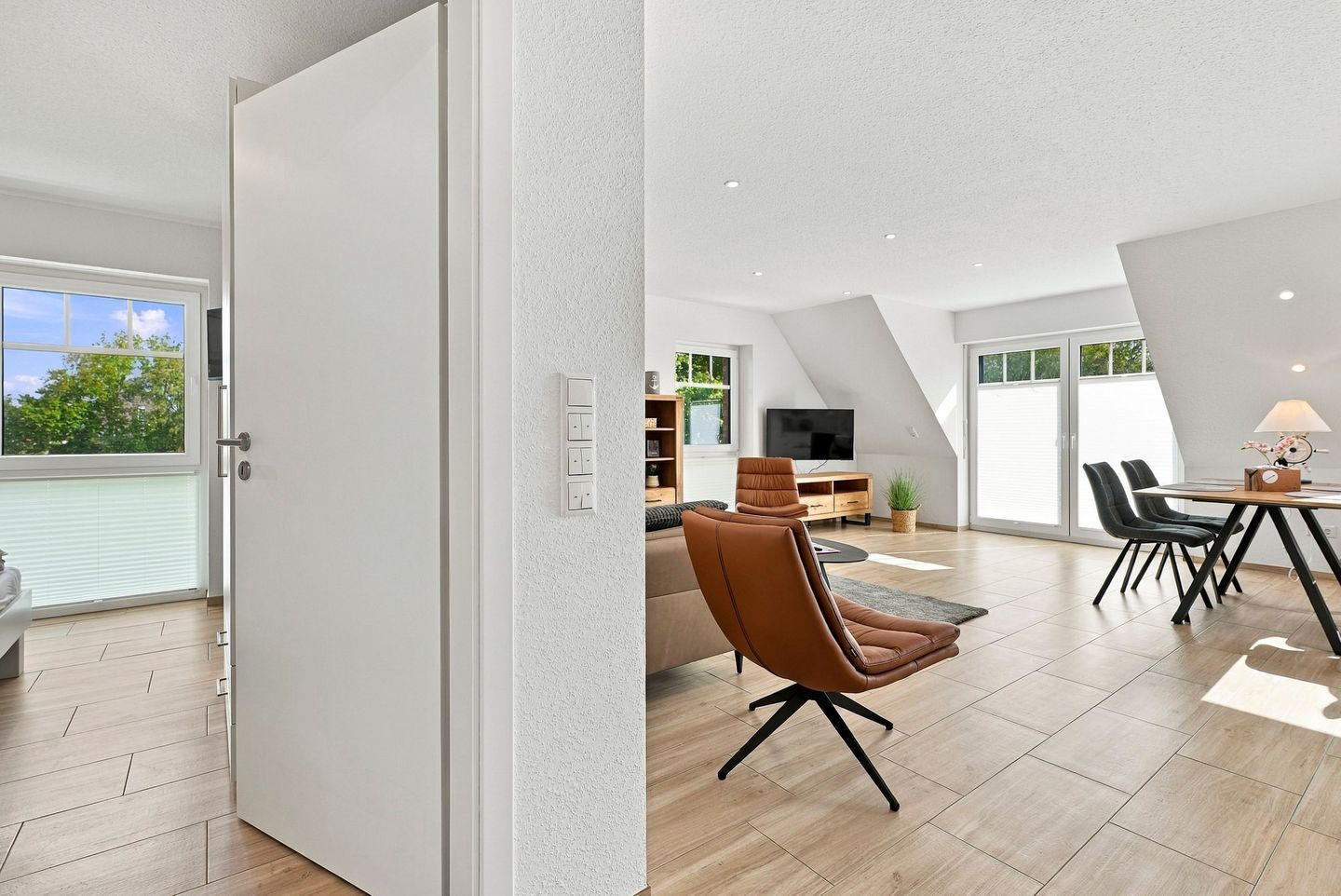 Ein zeitgemäßer Wohnraum mit Essbereich, einer Couch und einem Fernseher.