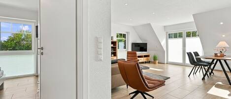 Ein zeitgemäßer Wohnraum mit Essbereich, einer Couch und einem Fernseher.