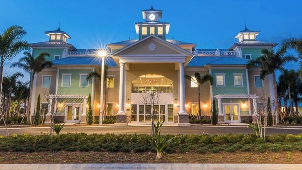 A large hotel with a central entrance, two towers, and a clock. - Disney Dreams Luxury Home with Private Water Park (Kissimmee)