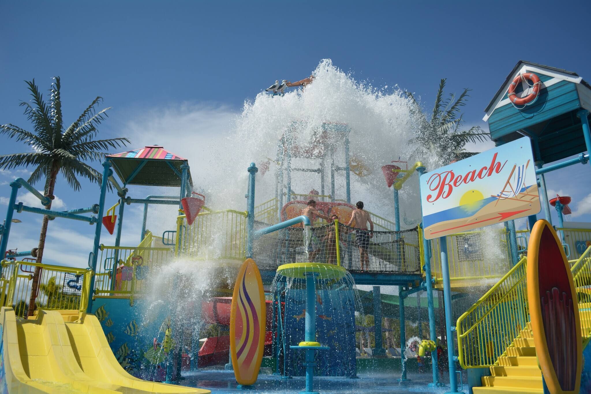 A water park with a slide, splash pad, and a sign that reads 'Beach'.
