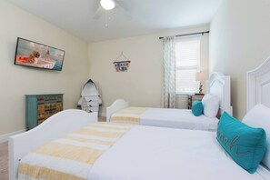 A bedroom with two beds, a ceiling fan, a television, a beach-themed sign, and a window with curtains. - Disney Dreams Luxury Home with Private Water Park (Kissimmee)