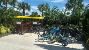 A paved area with bicycles and a red and blue cart with 'RENT ME AT THE AQUAPARK' signs. - Disney Dreams Luxury Home with Private Water Park (Kissimmee)