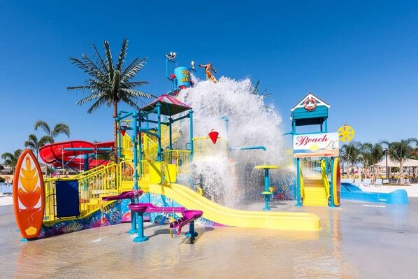 Un parque acuático con un tobogán gigante, una máquina de olas y un edificio con temática de playa.