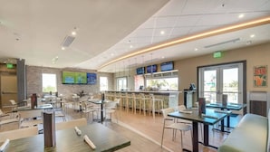 A restaurant with multiple tables and chairs, a bar area, and a television screen mounted on the wall. - Disney Dreams Luxury Home with Private Water Park (Kissimmee)