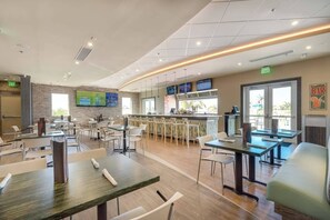A restaurant with multiple tables and chairs, a bar area, and a television screen mounted on the wall. - Disney Dreams Luxury Home with Private Water Park (Kissimmee)