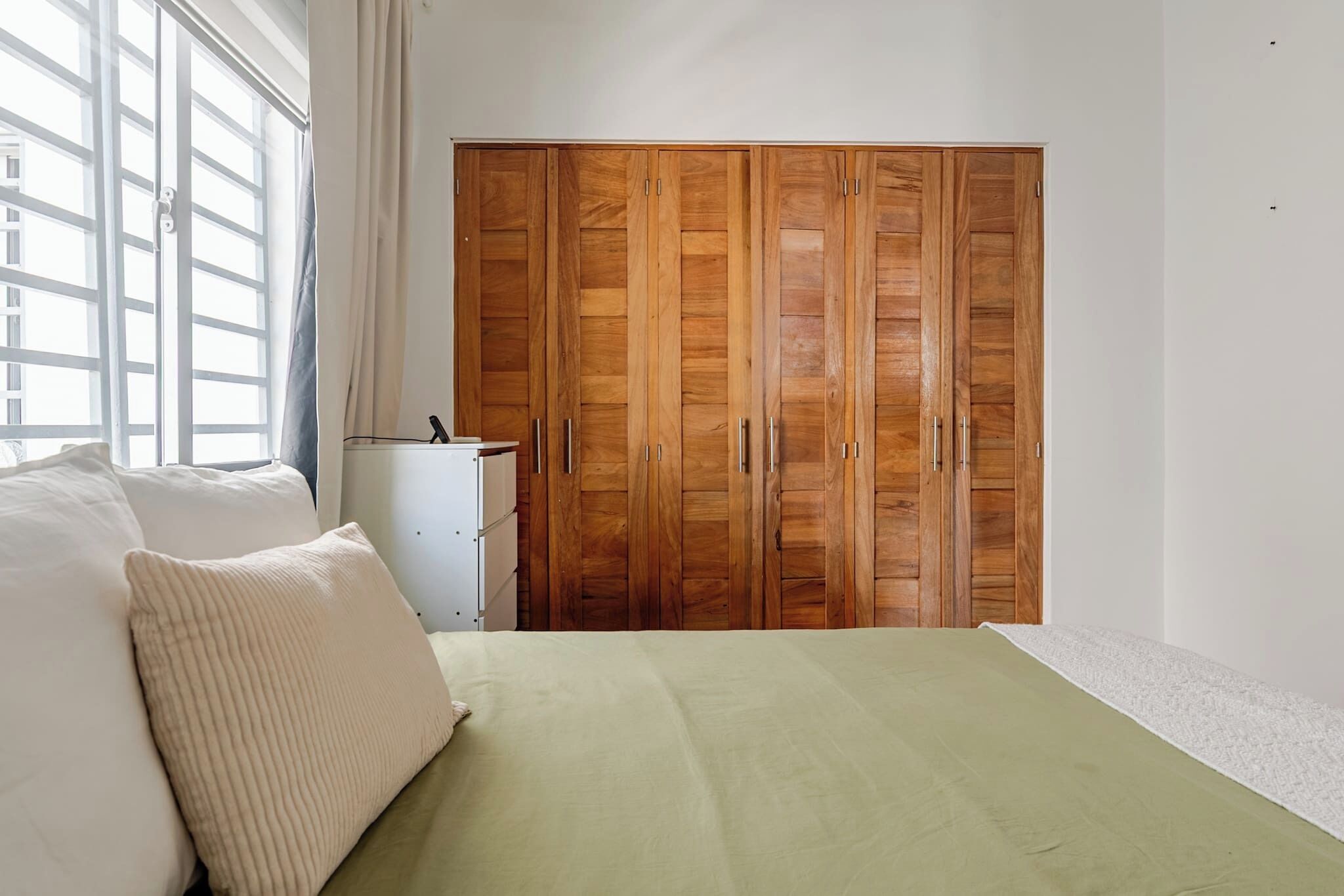 A bedroom with a bed, a wardrobe, and a window.
