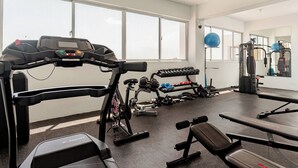Una palestra con attrezzature per esercizi, tapis roulant, manubri e una panca.