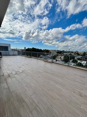 A rooftop terrace with a view of a cityscape, a railing, and a clear sky. - Modern 2BR Apartment Near Agora Mall (Santo Domingo)