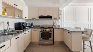 Una cucina moderna con un piano cottura in acciaio inossidabile, un forno a microonde e un lavandino.
