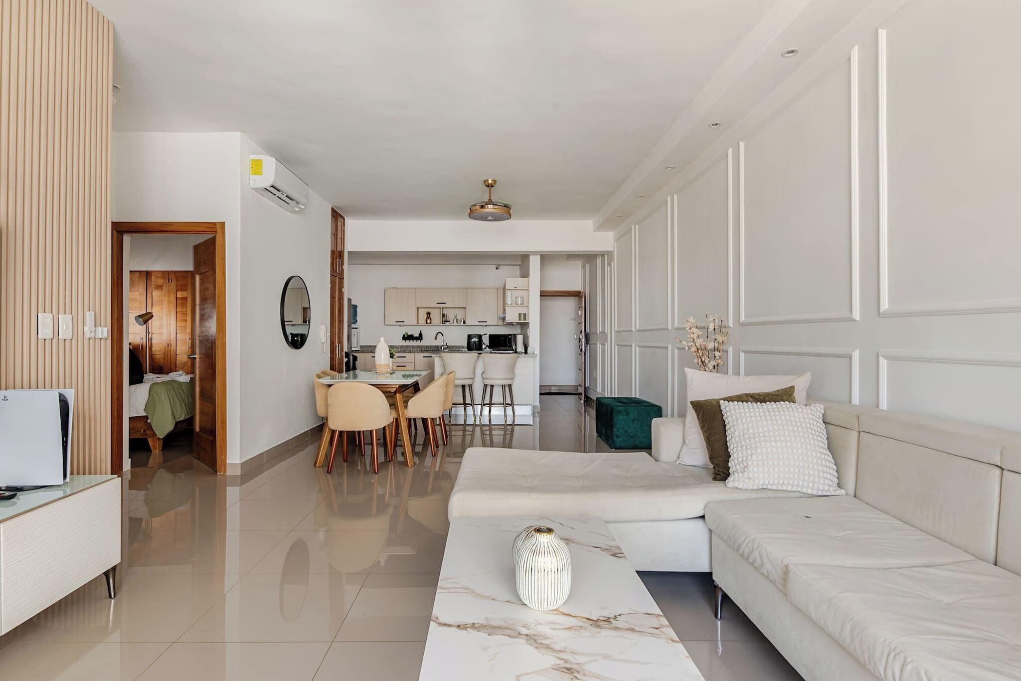 A modern living room with a sofa, a coffee table, and a dining area with chairs.
