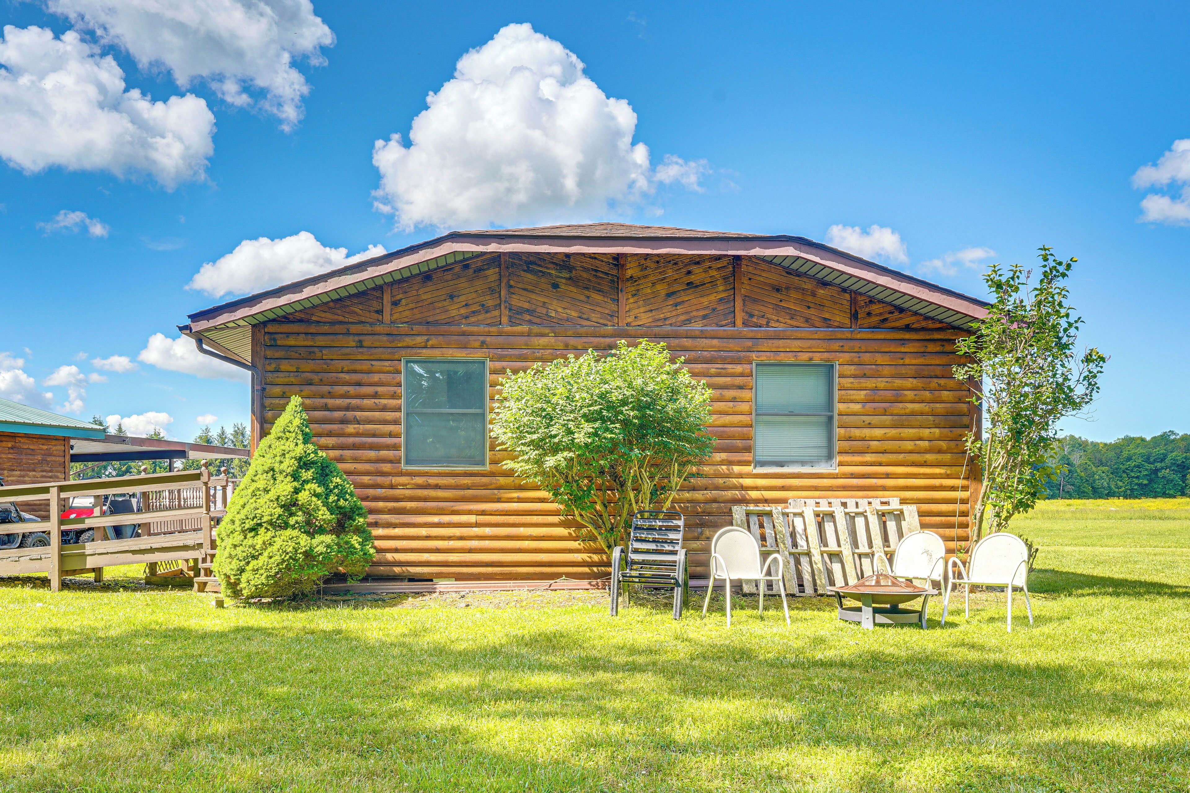 Une cabane en bois avec un toit en pente, deux fenêtres et une petite véranda comprenant une chaise et une table.