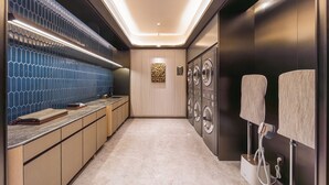 Un baño moderno con pared de azulejos, un lavamanos, un espejo y un perchero para toallas.