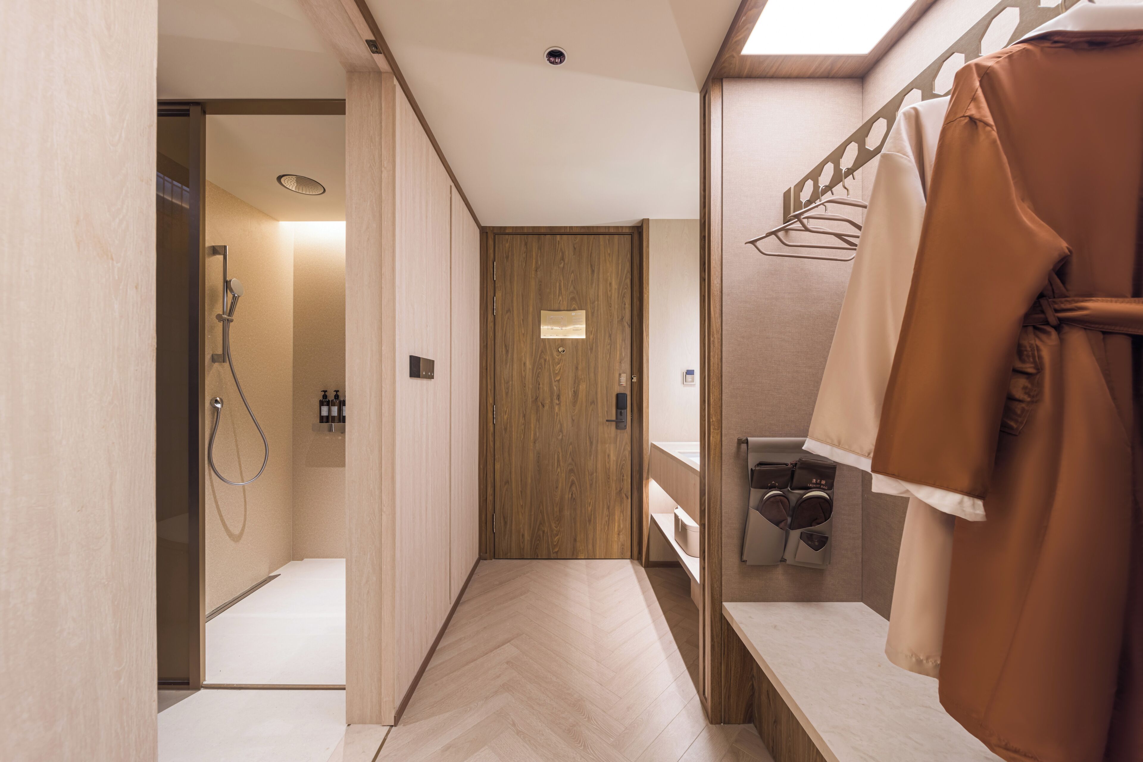 A modern bathroom with a shower, a wooden door, and a towel rack.