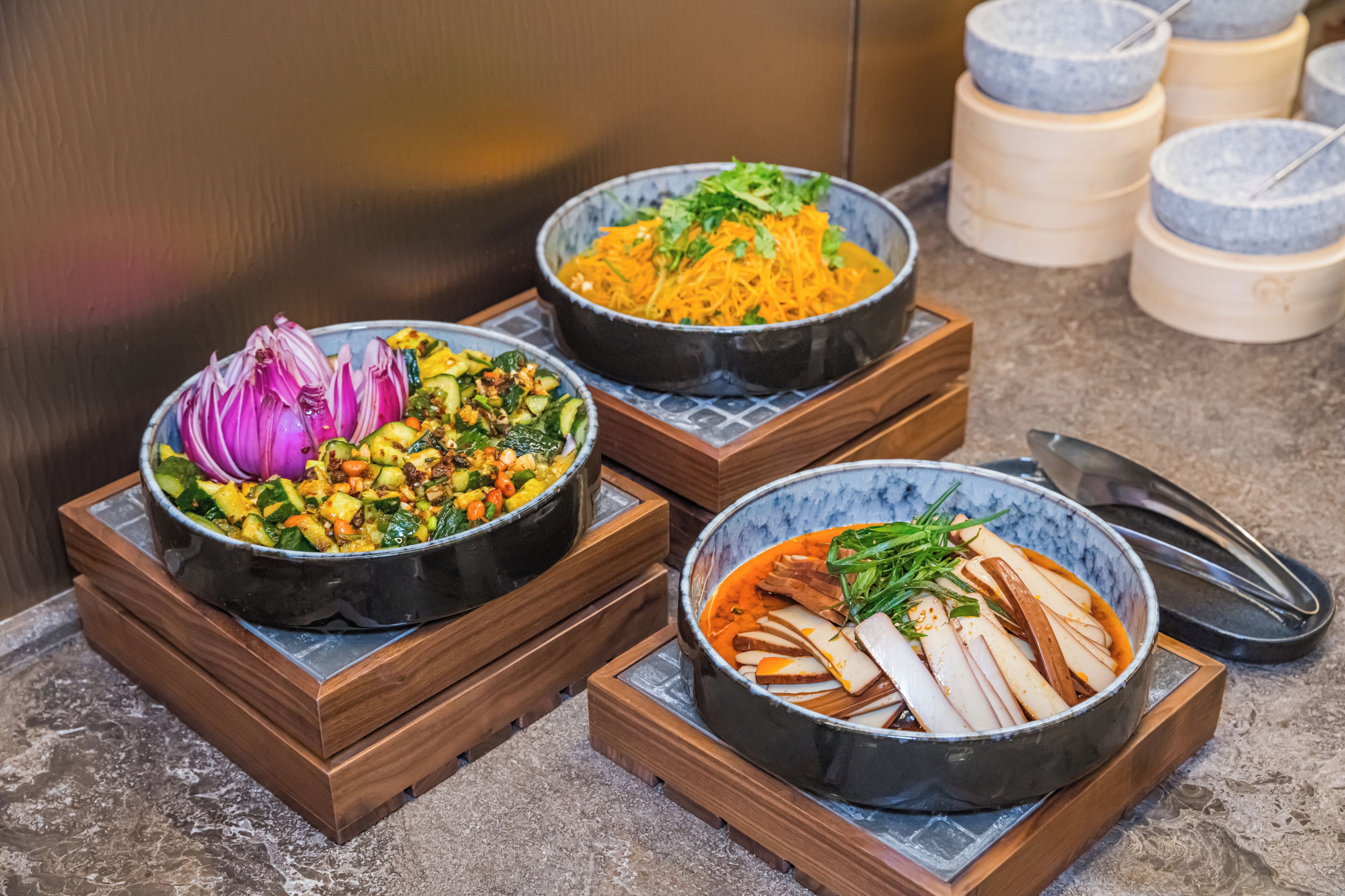Three bowls of food on wooden stands.