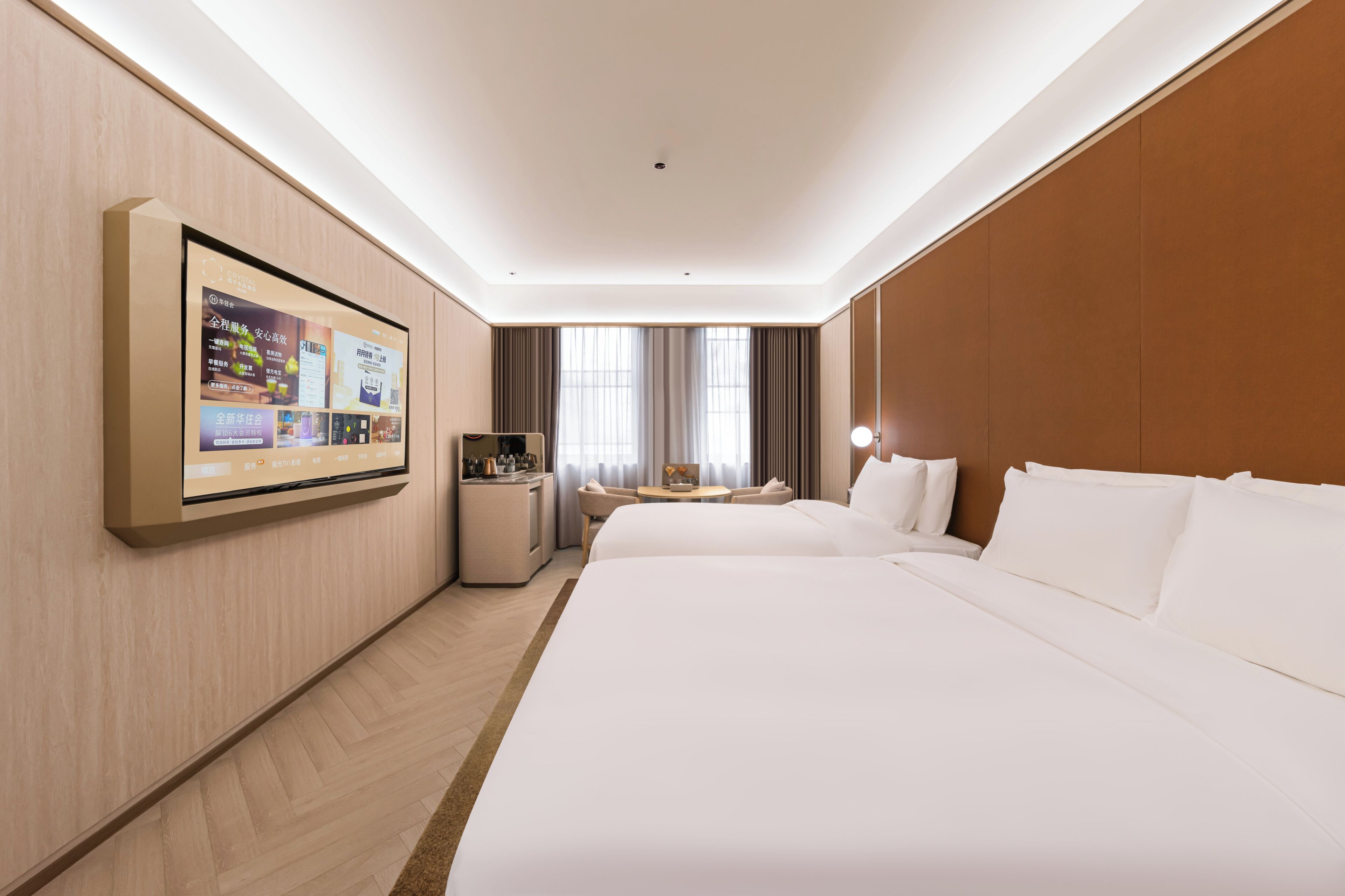 Une chambre d’hôtel avec un grand lit, un bureau, une chaise, un téléviseur fixé au mur et une fenêtre avec des rideaux.
